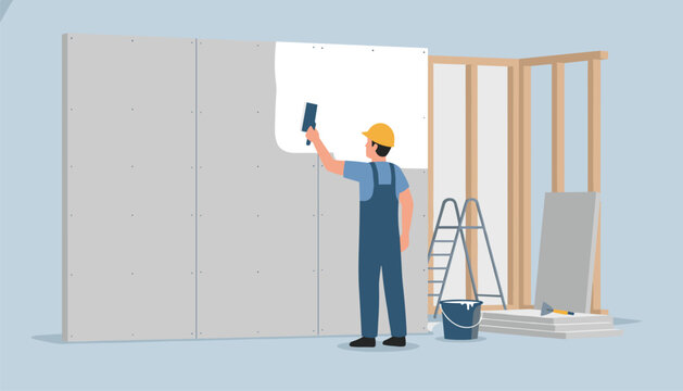 Construction worker in overalls and a hard hat applies plaster to a white drywall panel in a room under renovation.
