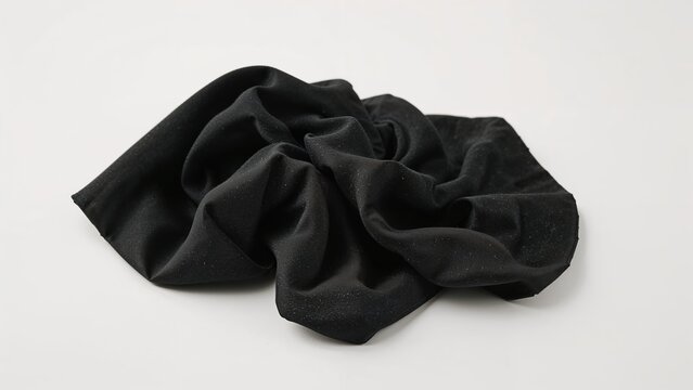A black fabric scrunchie or hair tie made of soft material.