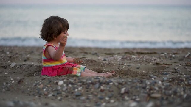 Adorable toddler baby playing on a beach with sand 