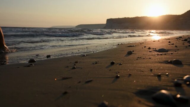 Man walking on beach during sunset, sea waves in the background 