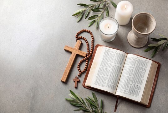 Holy Bible, wooden cross, rosary, candles and olive branches on stone