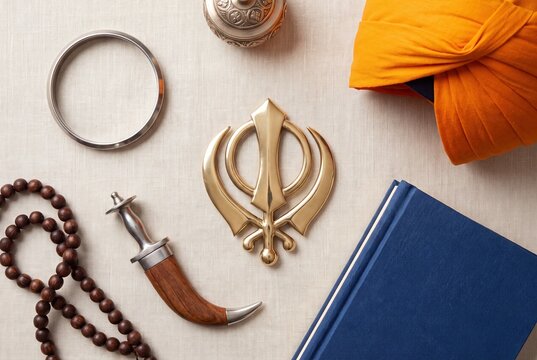 Sikh religious symbols Khanda Dastar Kara and holy book on fabric background