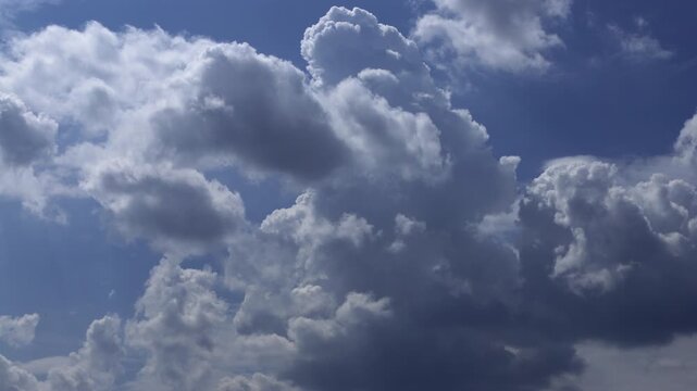 Time-lapse of Billowing cumulus clouds moving across a vibrant blue sky with natural light
