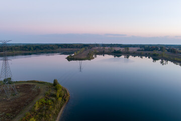 Fototapeta premium Power lines reflecting in calm Crandell lake water at sunrise