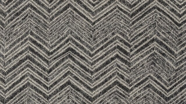 Close-up of a textile or carpet with a zigzag or chevron pattern in gray and black tones.