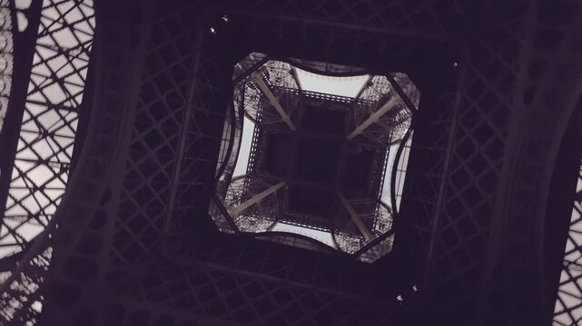 Unique worm's eye view of the Eiffel Tower's iron lattice structure creating an abstract and symmetrical pattern against the sky, showcasing the iconic landmark from an unusual perspective