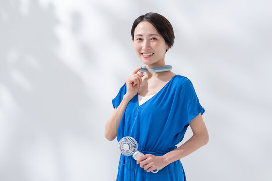 ハンディファンとネッククーラーを使う女性