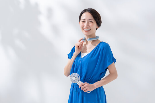 ハンディファンとネッククーラーを使う女性