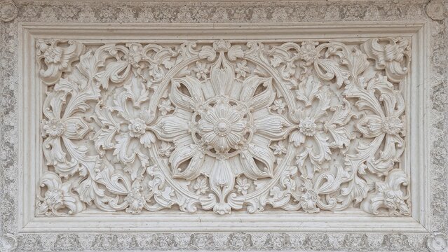 An ornate floral and leaf pattern carved in stone, forming a decorative rectangular panel.