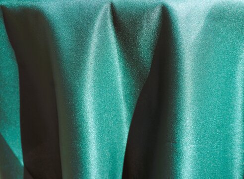 Abstraktes Motiv mit gr&uuml;ner h&auml;ngender drapierter Stofftischdecke als Hintergrund