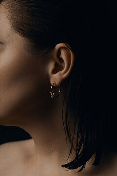Minimal gold hoop earring on female ear close up