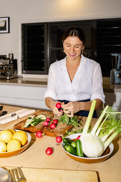 Smiling chef preparing fresh radishes for dinner party at home