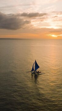 Tropical seascape with sunset reflection on water and sailing boat in Boracay, Philippines. Vertical view.