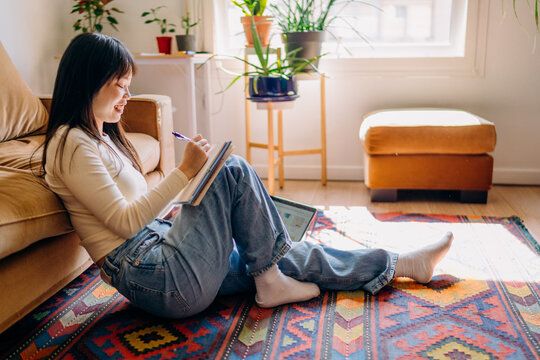 A woman writing in a notebook sitting on the floor