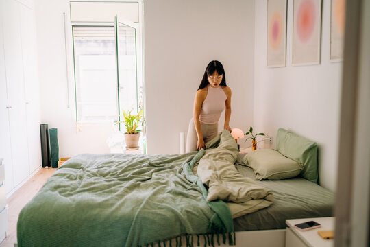 A woman spreading a bed