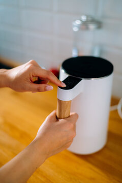 Woman's hands turn on the kettle