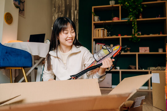 A woman opening a box sitting on the floor