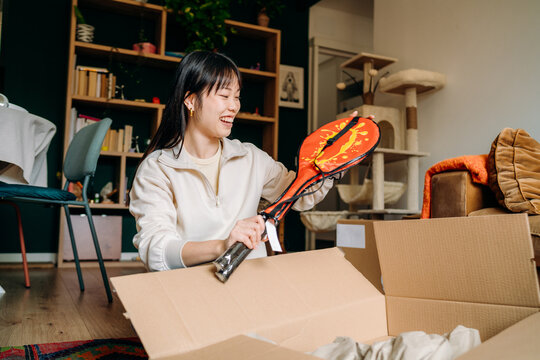 A woman opening a box sitting on the floor