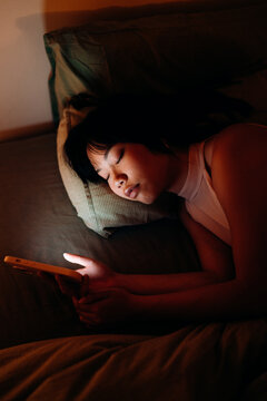 A woman uses a mobile phone in the bed at night