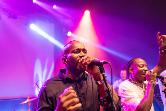 Black male performer singing into microphone during live concert