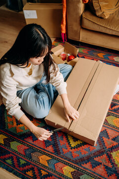 A woman opening a box sitting on the floor
