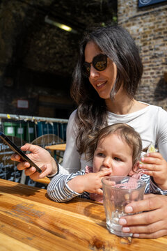 Mother with Smartphone While Baby Girl Enjoys Terrace Stop