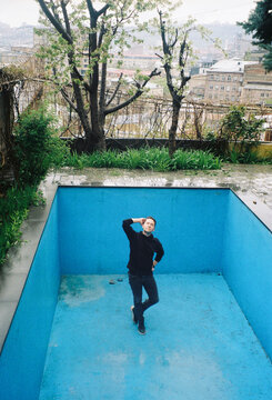 Person Stands in Empty Pool With Blue Walls and Wet Ground