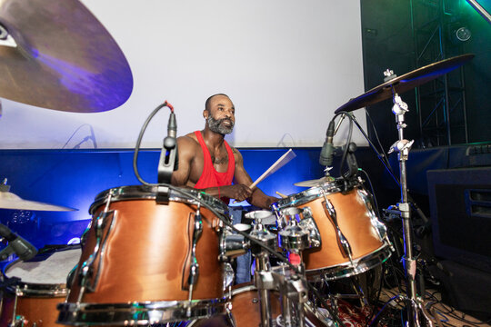 Black man playing drums performing live on stage