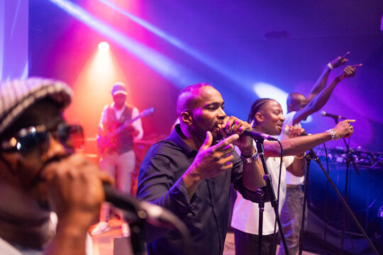 Black musicians performing live concert with microphones and