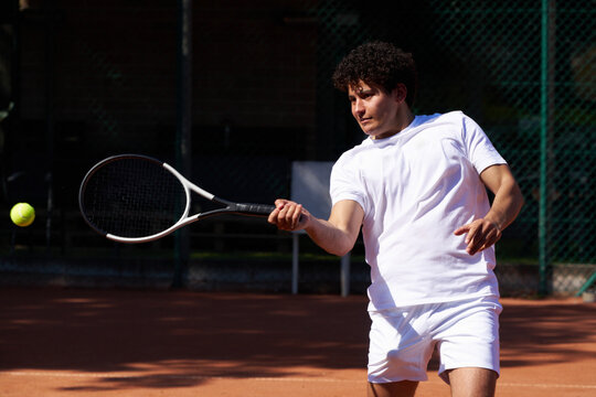 Player Hits a Tennis Ball on a Court in Warm Weather