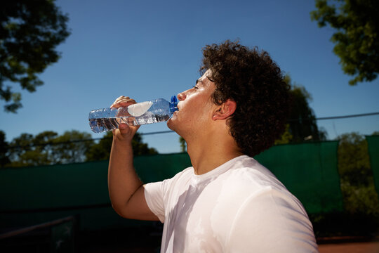Young Athlete Drinks Water After Workout in Sunny Weather