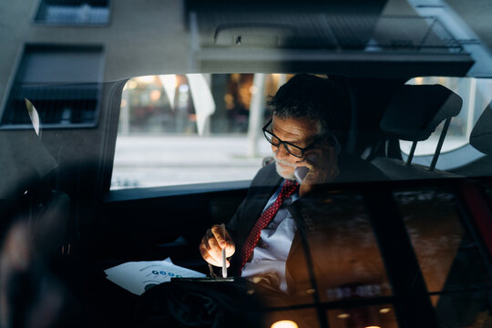A man using a mobile phone and a tablet in the car