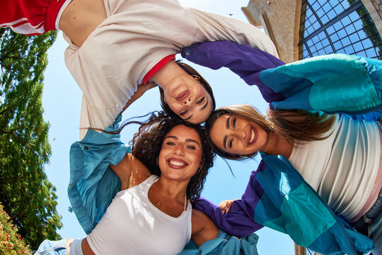Friends smile together in a circle at a sunny outdoor location