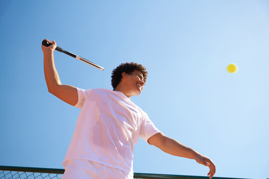 Young Player Hits a Tennis Ball During a Match on a Sunny Day