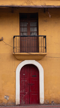 Traditional Portuguese-style yellow building with red wooden door in Panaji, Goa