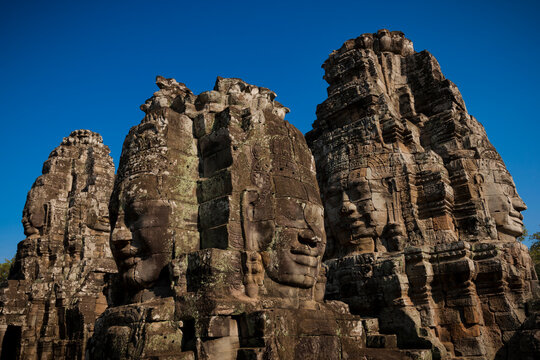 Ancient Bayon face towers beneath clear blue sky