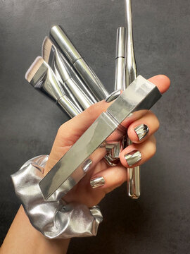 Silver shiny makeup beauty products and silver nails closeup 