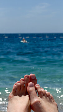Sandy feet propped up toward a sparkling blue sea