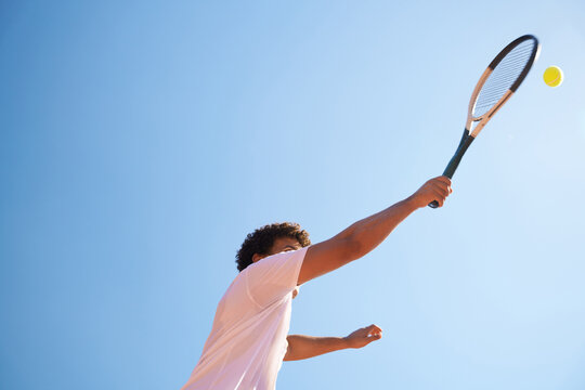 Tennis Player Serves Ball Under Clear Blue Sky During Daytime