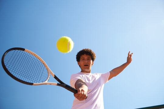 Young Person Plays Tennis on a Court With Clear Blue Sky