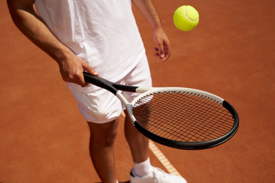 Tennis Player Holds Racket While Playing with a Ball