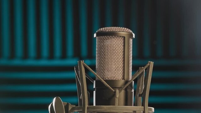 Slow motion colorful studio shot of voiceover dialogue podcast microphone on stand in close-up detail with acoustic foam in recording space with dark background and bright lighting of broadcast vo mic