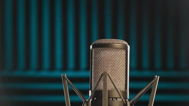 Slow motion colorful studio shot of voiceover dialogue podcast microphone on stand in close-up detail with acoustic foam in recording space with dark background and bright lighting of broadcast vo mic