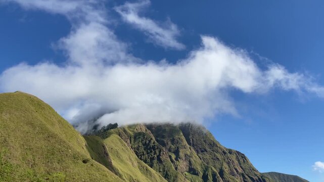 Scenic view of green mountains and clouds under blue sky.