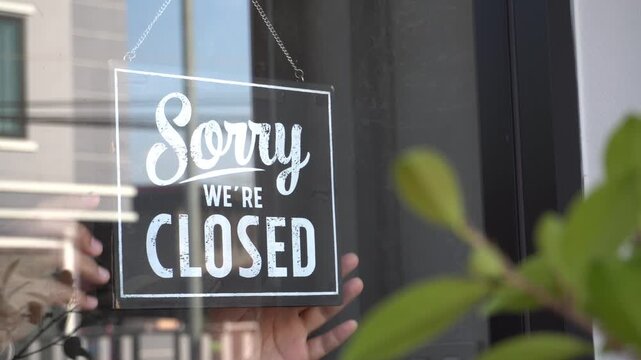 Flipping open to closed sign on a glass store door