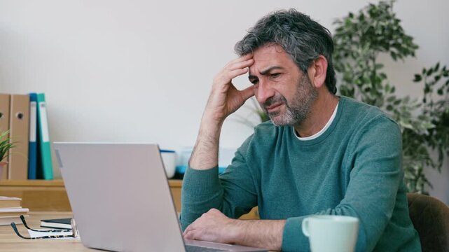 Video of tired man with headache working with laptop at the office