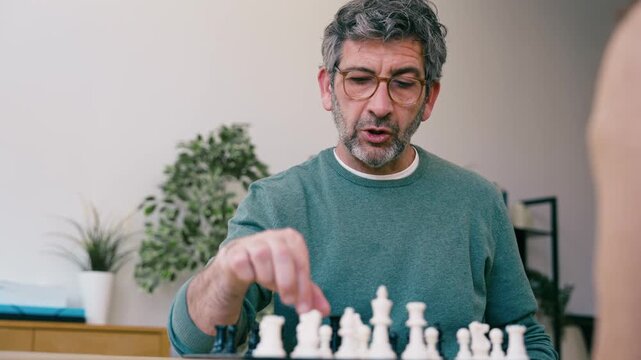 Video of mature man playing chess with a friend at home