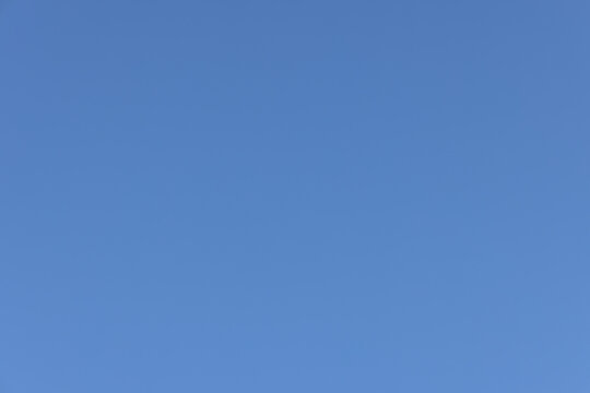 A plain cloudless blue sky fills the entire frame with an even natural gradient and clean central copy space for simple graphic design.