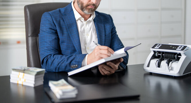 Banking and currency management. Financial services. Business solution. Businessman working in exchange office. Man making notes at money counter. Economic wealth and value investing