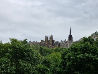 Obraz premium Old buildings behind trees on a cloudy day in Edinburgh, Scotland